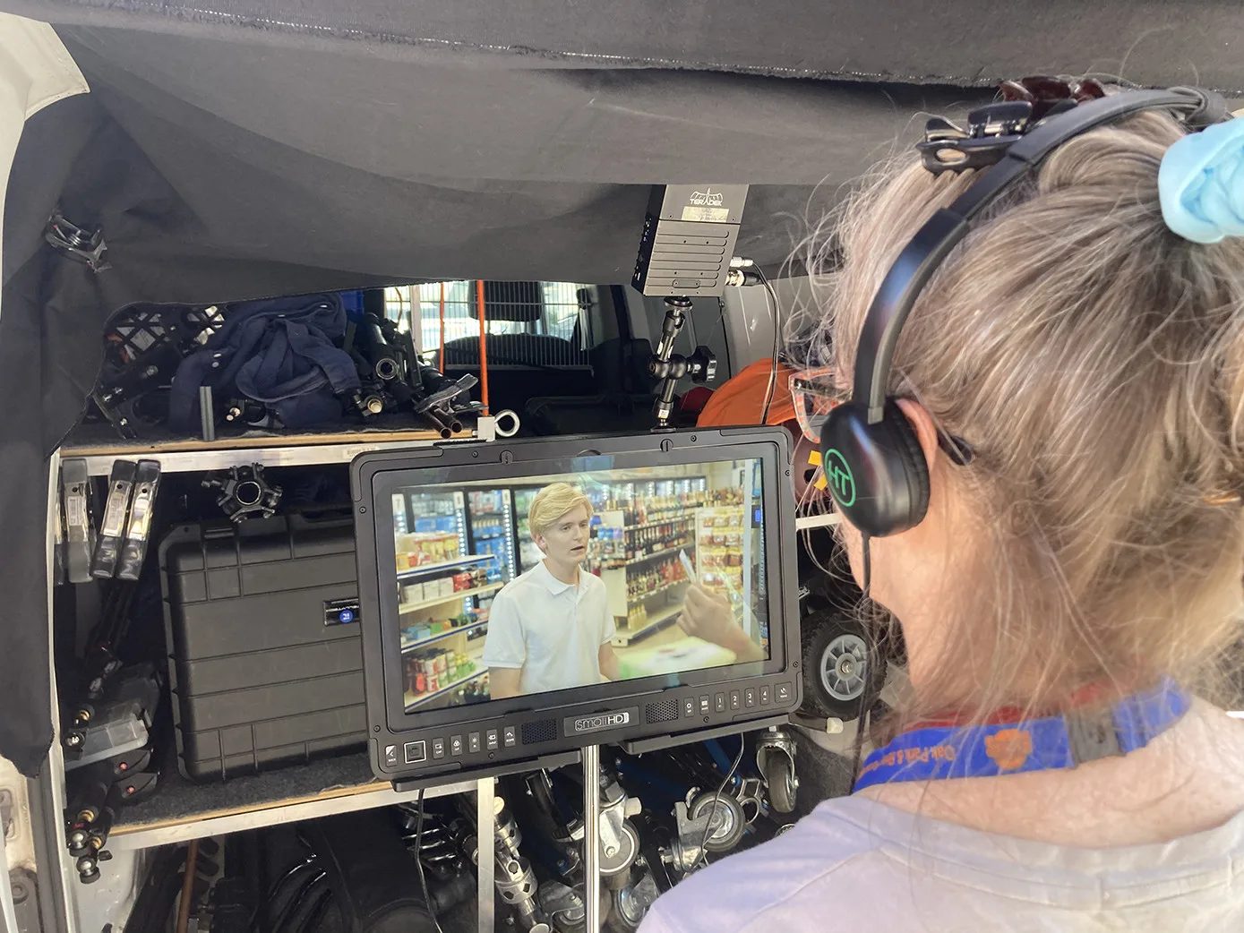 EXILE, Scene 6, Sunday, July 25, 2021. Daniel McNeill (Liquor Boy) tries unsuccessfully to pass off a fake ID, but Stanley Coelho (Liquor Store Owner) isn't fooled. Outside in the parking lot, writer/director Martina Reese watches the take on a monitor.